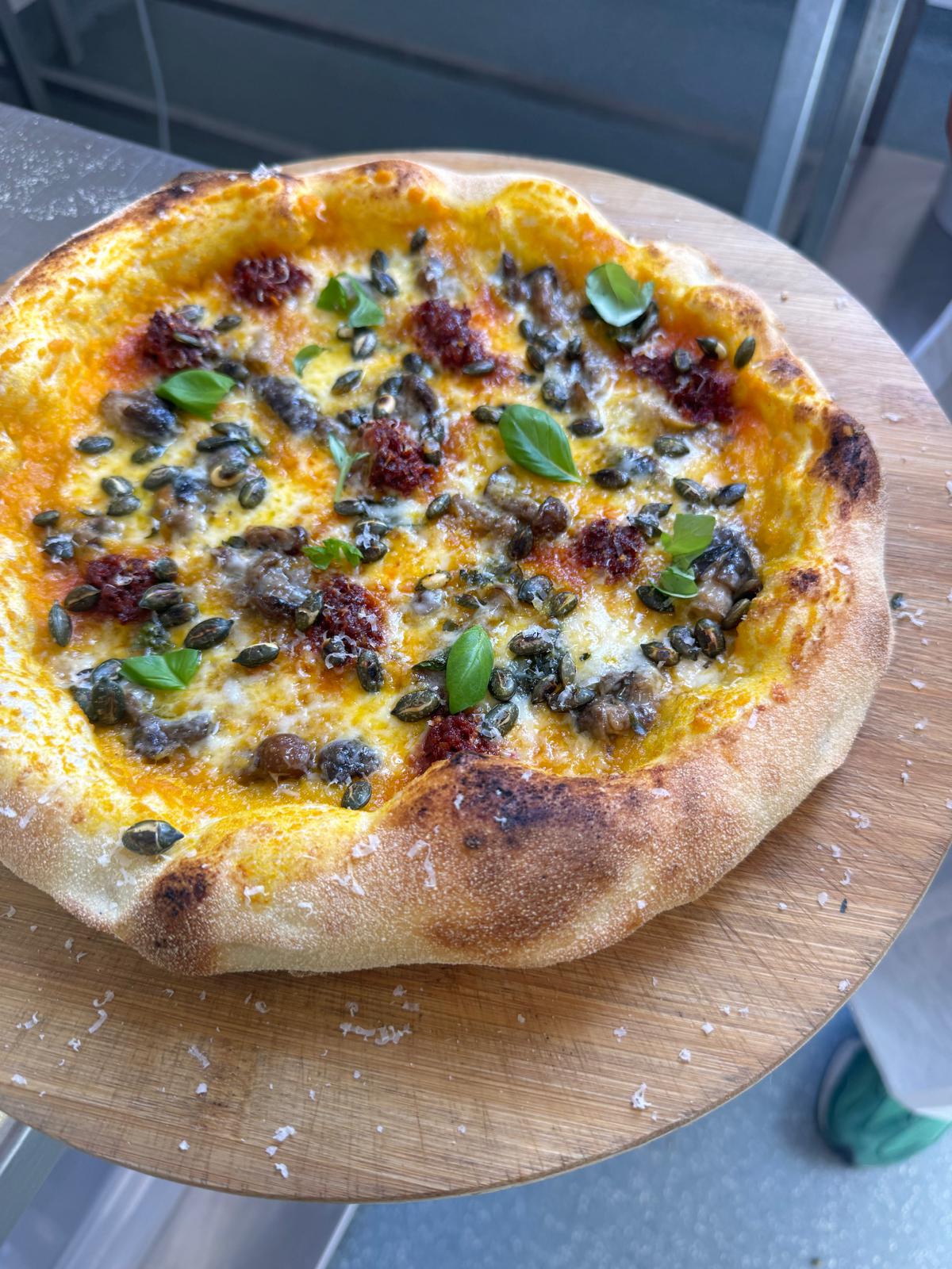 A freshly baked pizza with a golden-brown crust, served on a round wooden board.